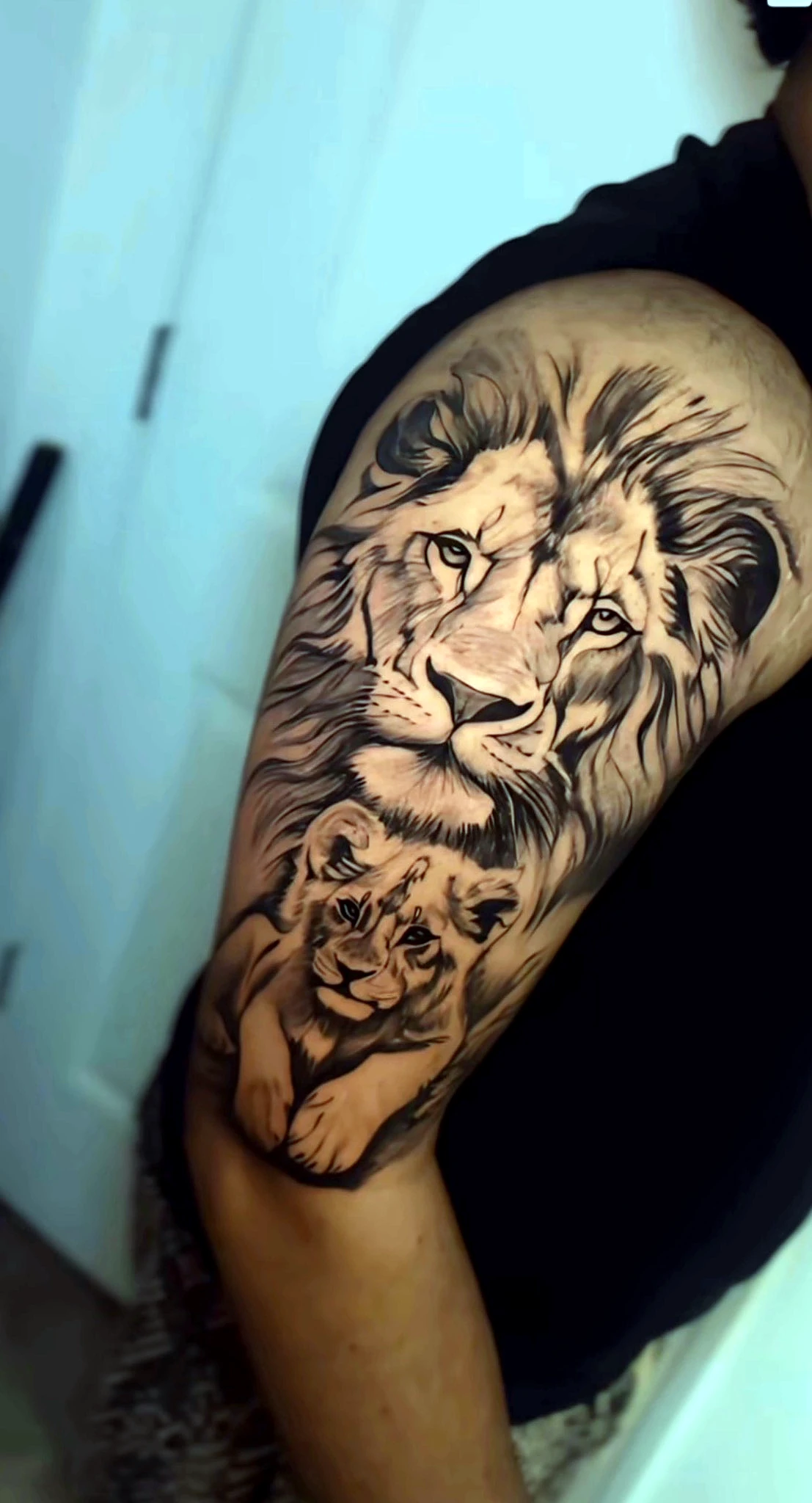 Black and grey realism lion and cub on the upper arm by Rav Singh at Inkology